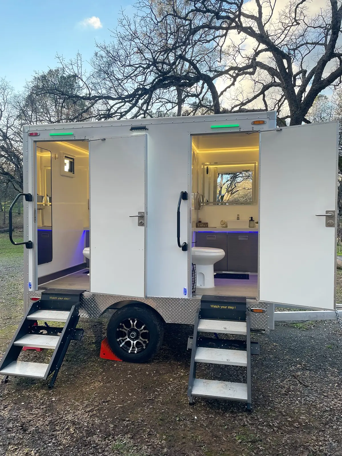 Lit restroom trailer at an evening event
