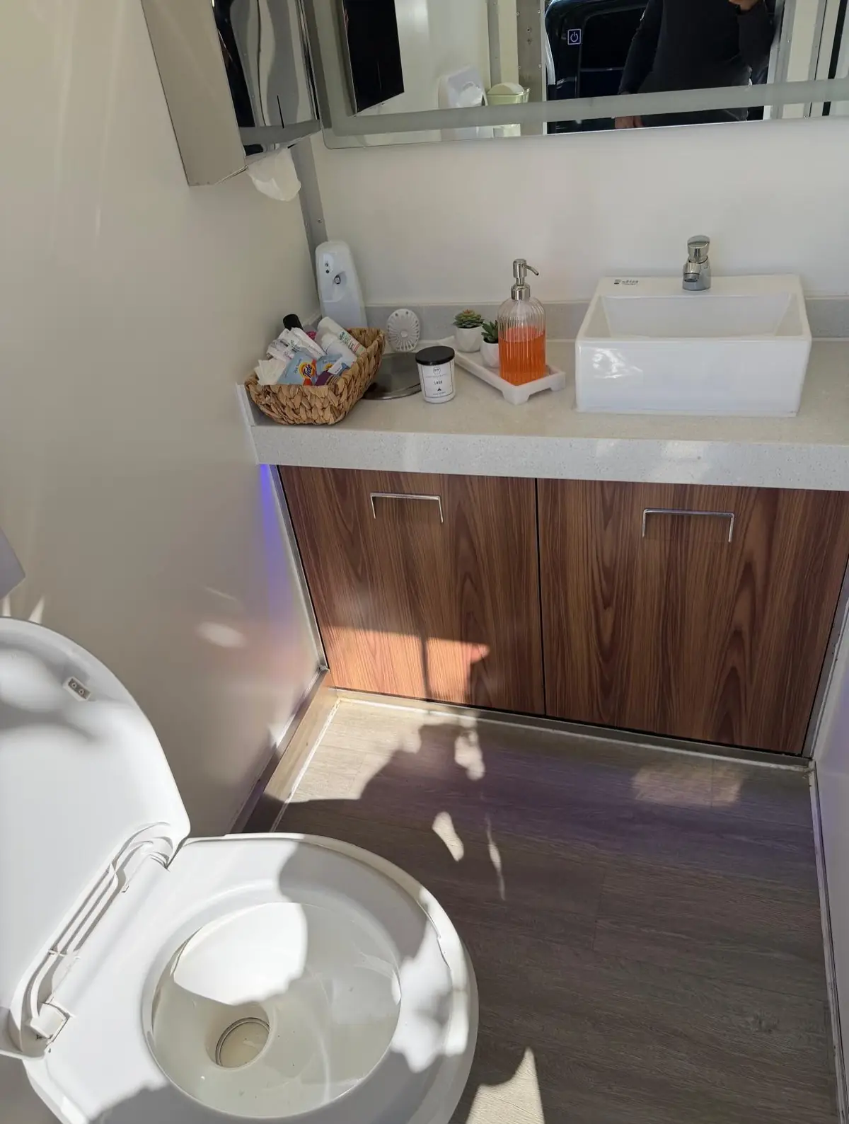 Wood vanity and vessel sink inside a luxury restroom trailer