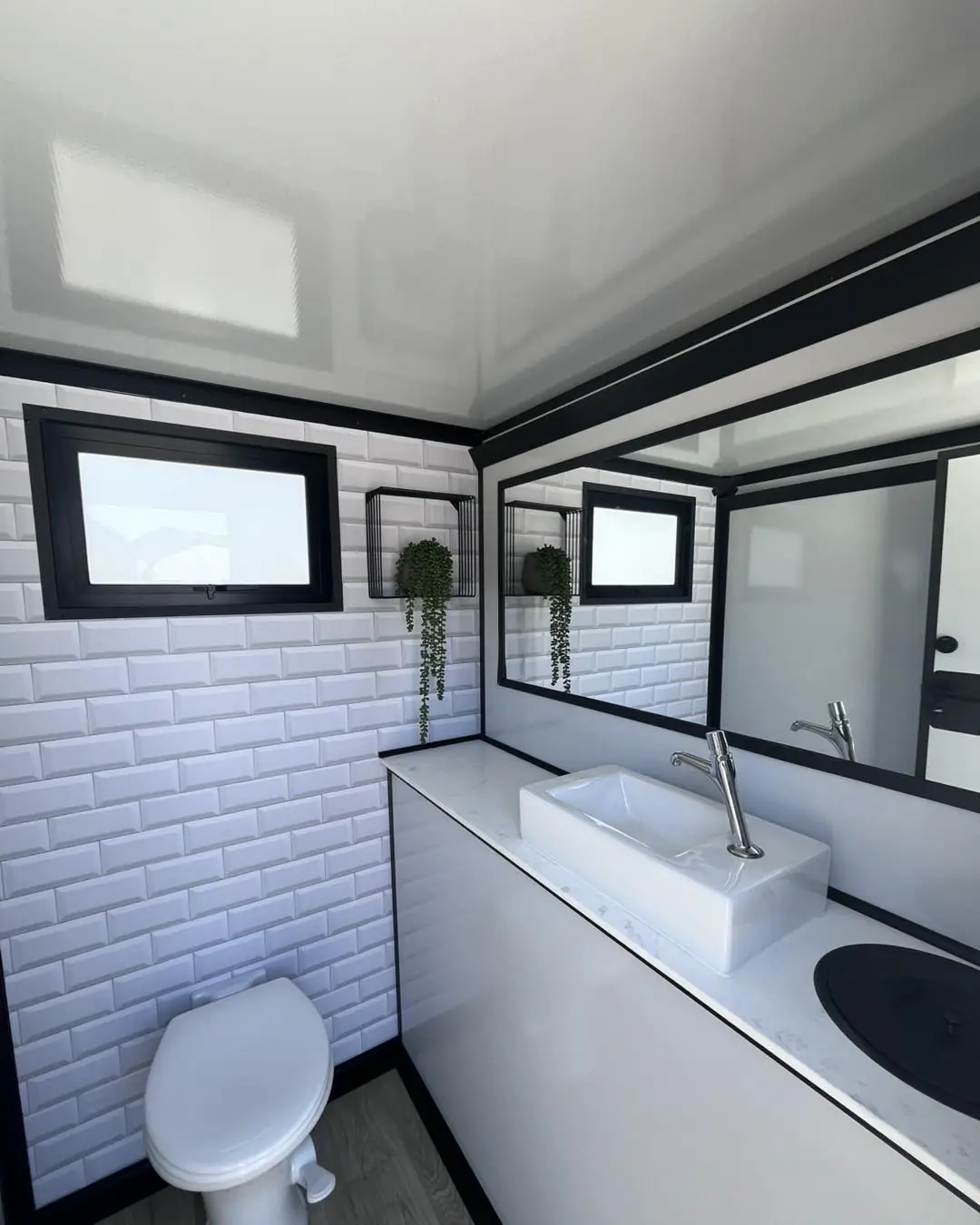 Restroom trailer interior with tiled walls, vanity sink and window
