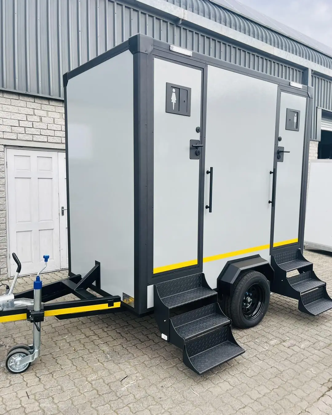 Gray two-door restroom trailer with fold-down steps